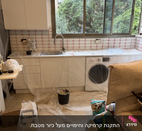 מטבח בשיפוץ עם אריחים חדשים, דלי וחומרי בניין